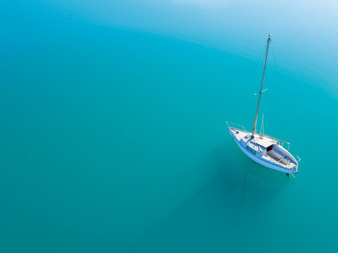 Aerial view of alone yacht sailling on azure water