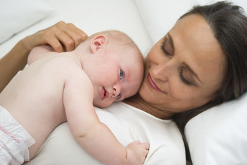 Mother holding baby daughter on bed