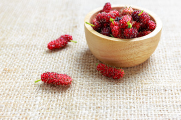 Red mulberry in wooden bowl and on cloth floor
