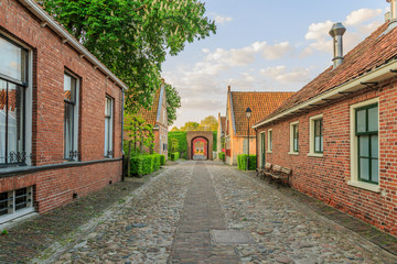 Fototapeta na wymiar Streetview with houses, roads, trails and landscaping as gardens and trees in the historic fortress town of Bourtange, Groningen in the Netherlands.