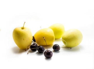 Isolated yellow apples and black cherries