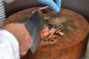 hand slicing meat on the wood
