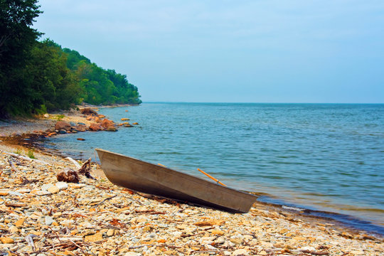 Typical fishing boat on the pebbled shore. Old fishing vessel on beach. Tinted photo.
