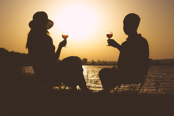 Vintage couples, men and women with glasses of wine in his hand on the river bank in the summer on...