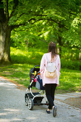 Fototapeta na wymiar Happy mother walking with baby stroller in park