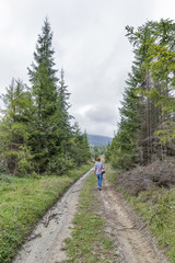 Woman hiking dirty rural forest road in Carpathian mountains