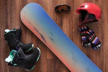 Fototapeten set of snowboard boots, helmet, gloves and mask on wooden © Аrtranq
