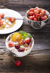 Healthy breakfast snack. Marble Portion bowl full of cherry smoothie with natural yogurt, ripe berries, fruits, bee pollen, berry syrup on a wooden background