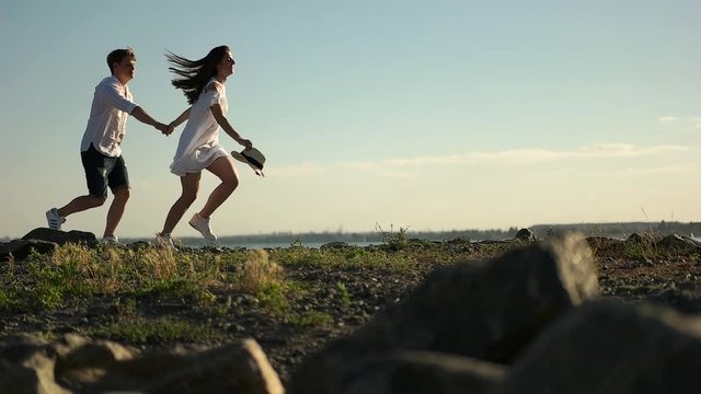 Couple running along the rocks on promenade.