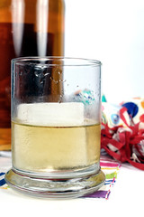 close-up of a glass of whiskey with party favors in the backgroun