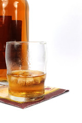 Close-up of whiskey on the rocks, in background is bottle