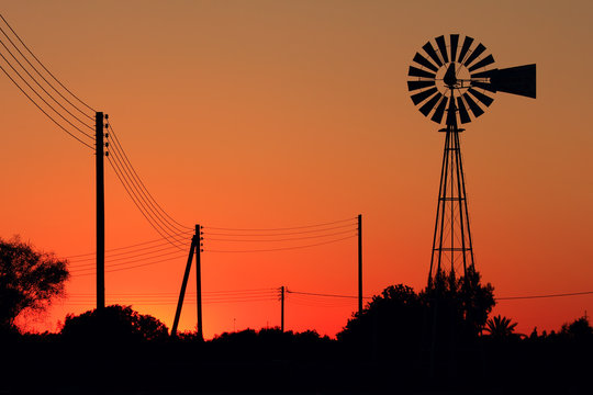Silhouettes of wind generator at sunset.