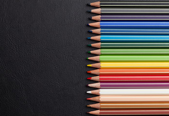 Colorful pencils over leather desk
