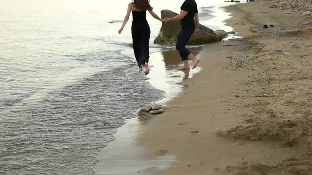 Couple running barefoot on the beach.