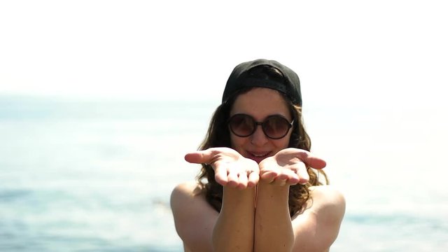 Girl in sunglases and baseball cap smiling.