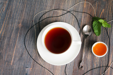 Cup of tea, honey, mint leaves and spoon on the old rustic wooden table
