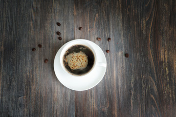 Black hot coffee in a white cup on a wooden table. Special light.