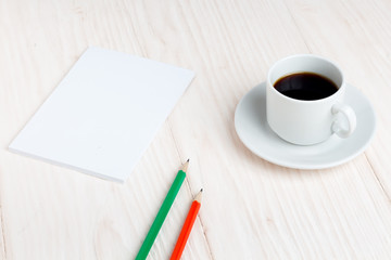 Cup of coffee, a notebook, pencils on the table