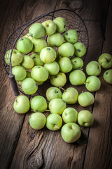 Green apples in a metal basket.