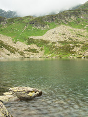 Mountain lake on the background of the Greater Caucasus mountain range north with fog