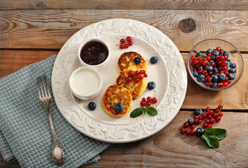 Cheesecakes with cottage cheese on a plate with sour cream and j