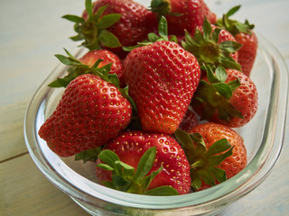 strawberries in a white plate. A plate of strawberries is on aged wooden background