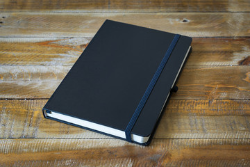Black notebook on a wooden background