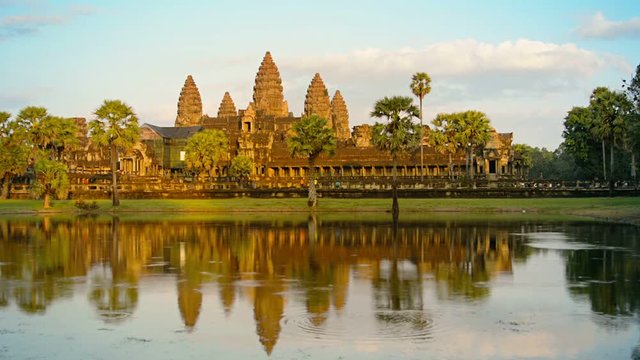 Angkor Wat temple in the afternoon light. Green grass and palm trees can be seen in front of the temple. Cambodia, Asia.