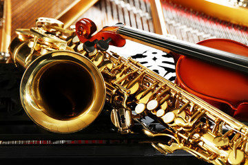Violin and saxophone lying on piano, close up
