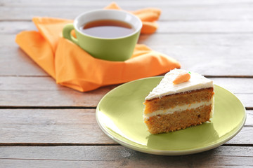 Piece of carrot cake with a cup of tea on wooden table