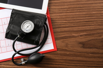Medical concept. Medical manometer, cardiogram chart on wooden background