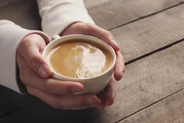 Man holding in hands cup of coffee on wooden background