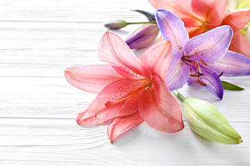 Beautiful lilies on light wooden background