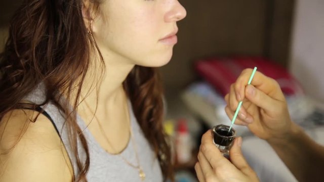 makeup artist paints the eyebrows of a beautiful girl model using brush