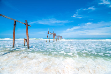 Ruins of wood bridge with beautiful wave and sky for copy space Broken wood bridge and waves crashing on sea Broken wood bridge and waves crashing on sea at Thailand