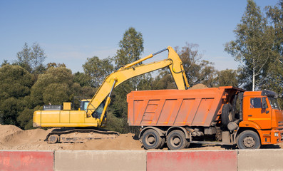 Excavator loading dumper truck tipper in sand