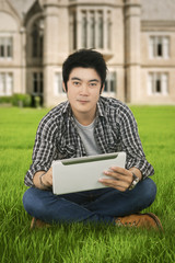 Male student uses tablet at school yard