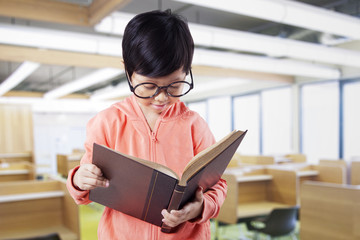 Naklejka premium Schoolgirl reads book in reading room