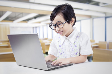 Schoolgirl uses laptop on desk in class