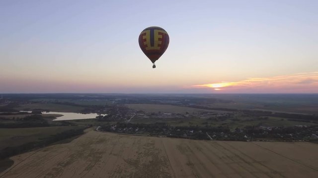 Hot air balloon in the sky over wheat field in the countryside.Aerial view:Hot air balloon in the sky over a field in the countryside in the beautiful sky and sunset.Aerostat fly in the countryside