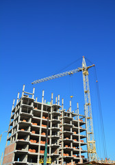 Construction industry with Crane, Copy Space, Sky Background. Crane Building New House on the Construction Site. Building cranes and building under construction.