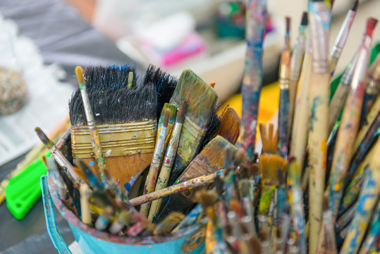 artist paintbrushes in dirty bucket.