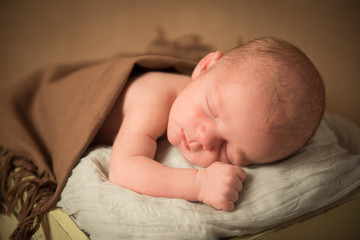 Newborn baby sleeping in a bucket. Close-up