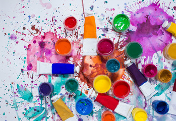 Paints, brushes and watercolor painted background. The workplace of the artist. Banner for school