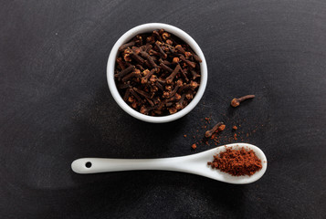 Clove spice in porcelain bowl and spoon