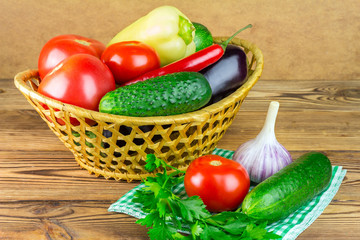 Group of backyard vegetables in wicker basket on wooden background.