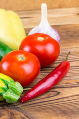 Backyard vegetables, tomatoes, cucumber, garlic, pepper, zucchini on wooden background.