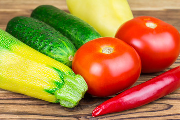 Backyard vegetables, tomatoes, cucumber, pepper, zucchini on wooden background.