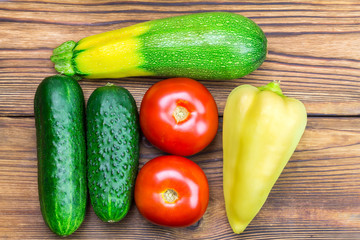 Backyard vegetables, tomatoes, cucumber peppers and zucchini on wooden background