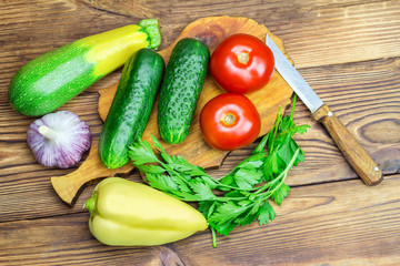 Backyard vegetables, tomatoes, cucumber, garlic, pepper, parsley on board, wooden background.